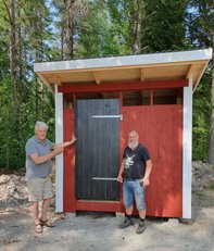 Åke Ö och Tobbe J framför det nybyggda dasset. Rött med vita knutar och svart dörr.