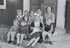 Svart vitt foto åtta barn och lärarinna på skoltrappa